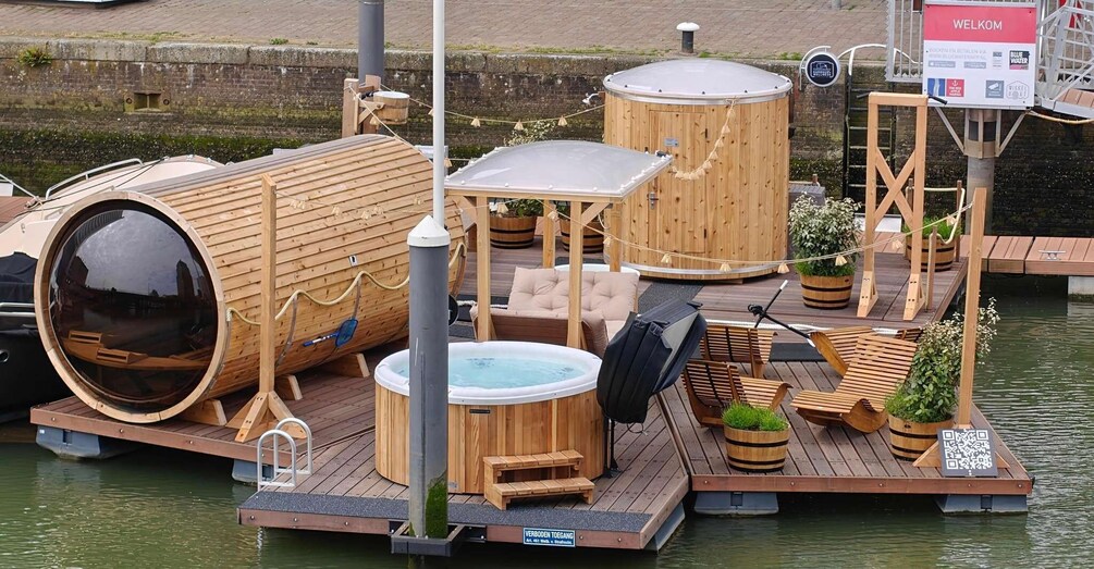 A floating wooden structure with a hot tub, seating, and a sign reading 'WELKOM.' 1