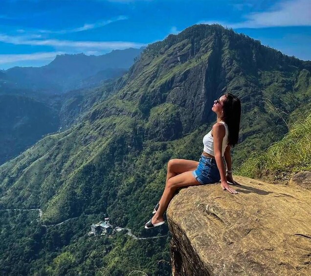 A person sitting on a rock overlooking a mountainous landscape. 1