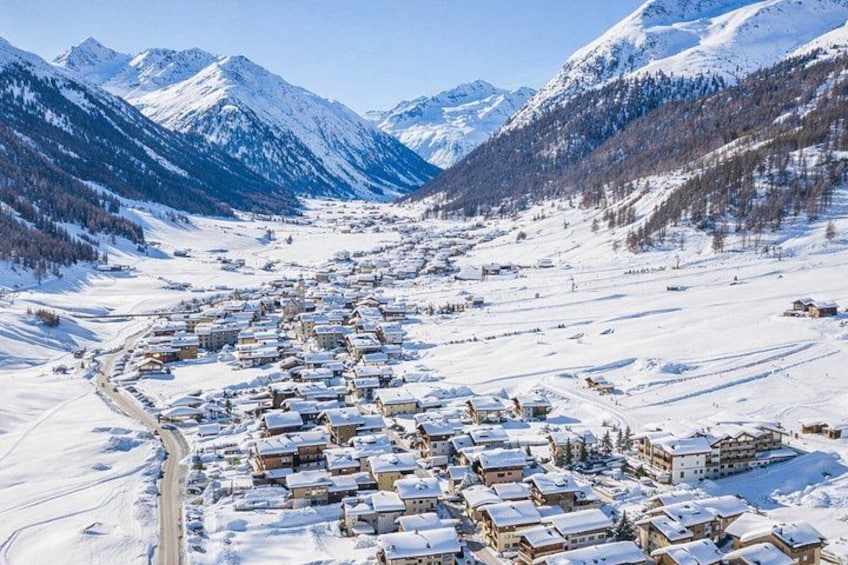 A snow-covered village with buildings and mountains in the background. 2