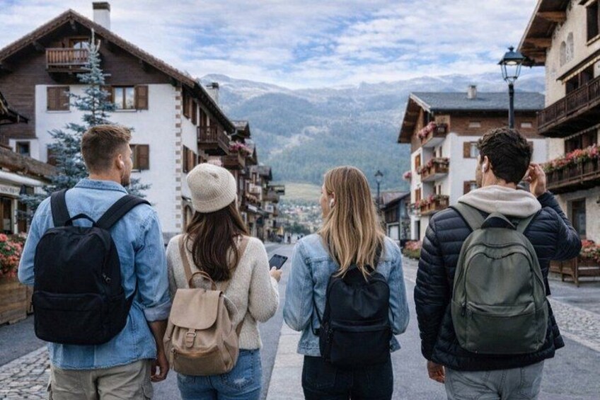 A group of people walking on a cobblestone street in a mountainous village with wooden buildings and a mountain in the background. 4