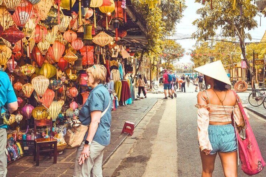 A street market with colorful lanterns and people shopping. 1