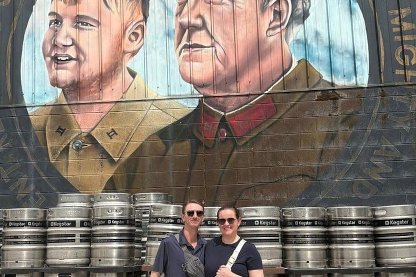 Un mural con dos figuras, un hombre y una mujer, y varios barriles de cerveza al frente. 2
