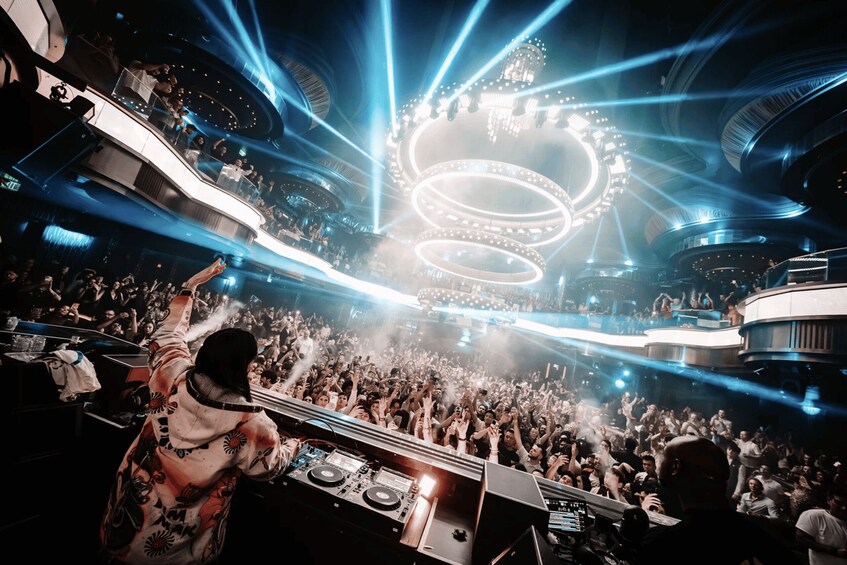 A concert with a DJ booth, a large crowd, and stage lighting. 3