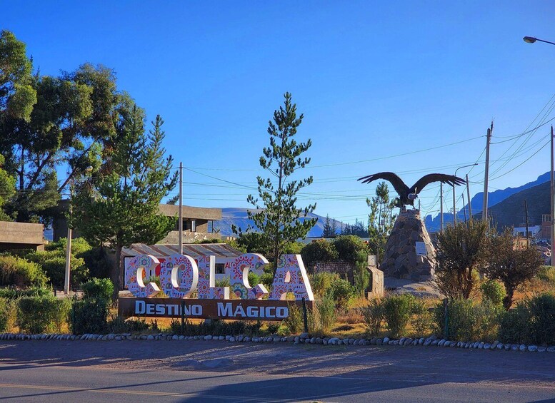 A sign with 'ROKA' and 'DESTINO MÁGICO' in colorful letters, a stone eagle sculpture, and a mountainous backdrop. 4