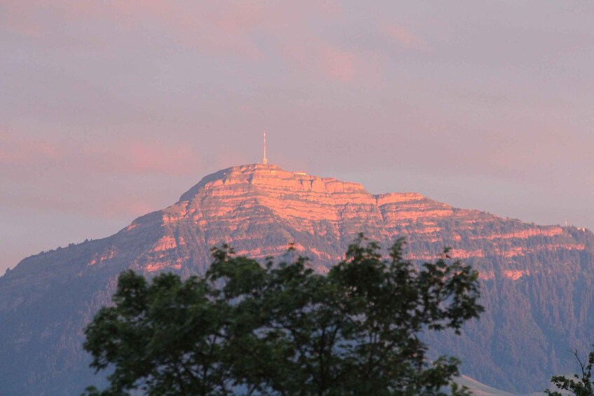 A mountain with a radio or TV tower on top, surrounded by trees. 2