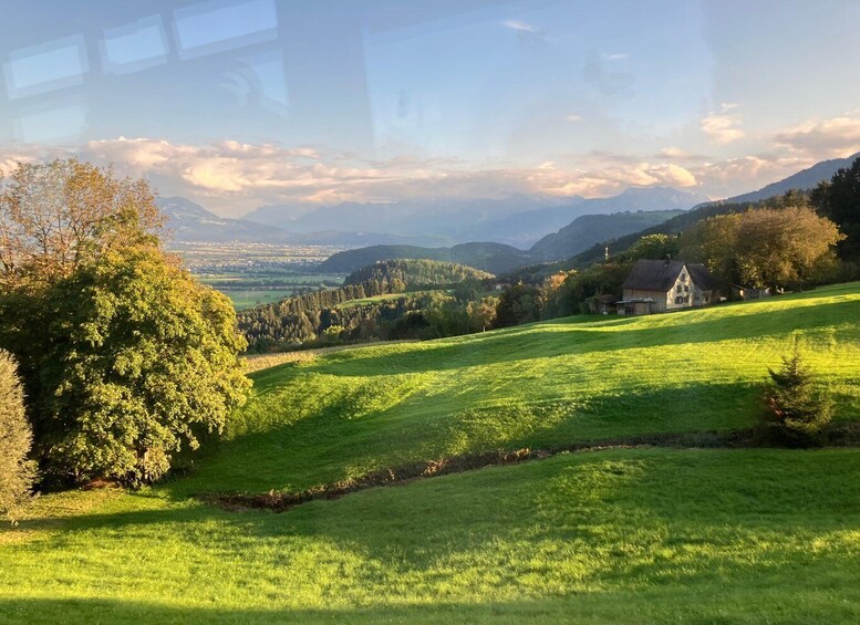 A rural landscape with rolling hills, a church, and a distant mountain range. 4