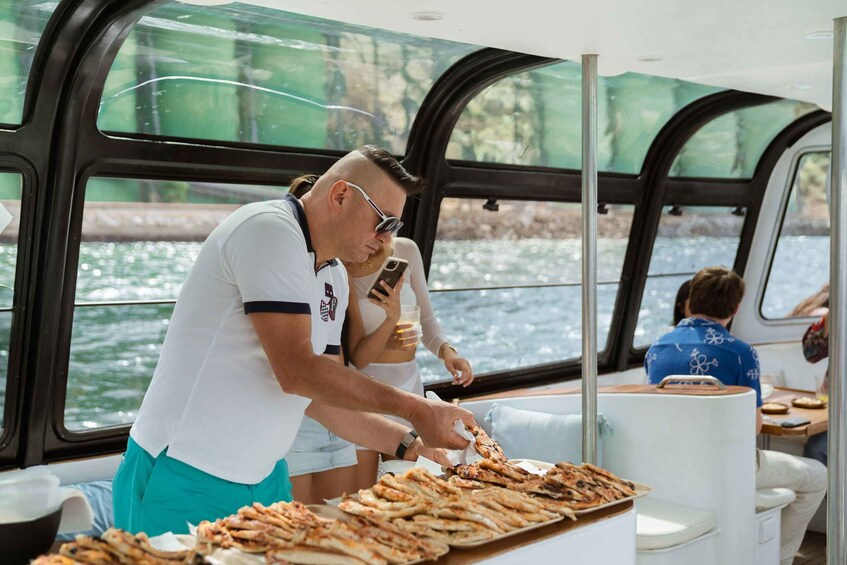 A boat with people dining and a man serving food. 4