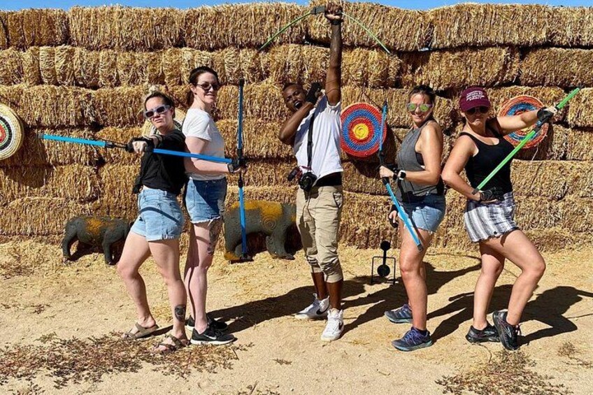 People playing a game with targets in a field with hay bales in the background. 1