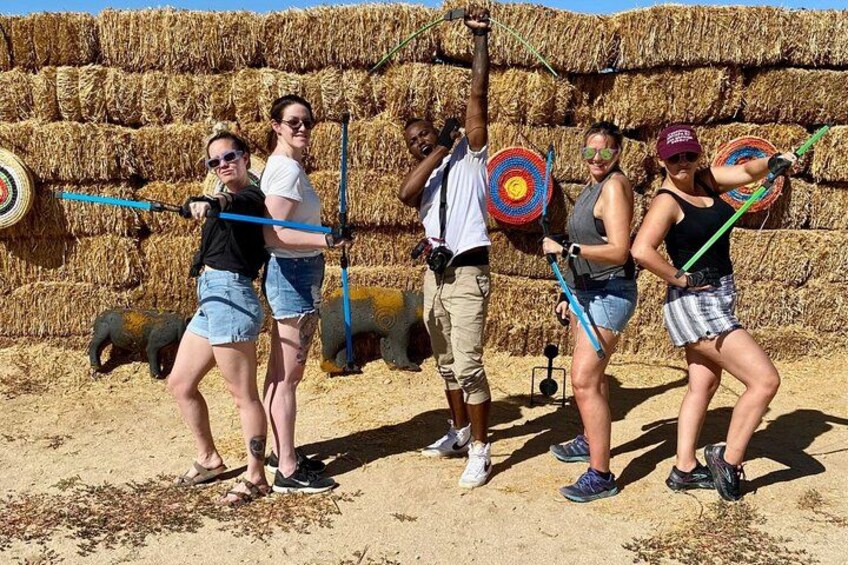 People playing a game with targets in a field with hay bales in the background. 1