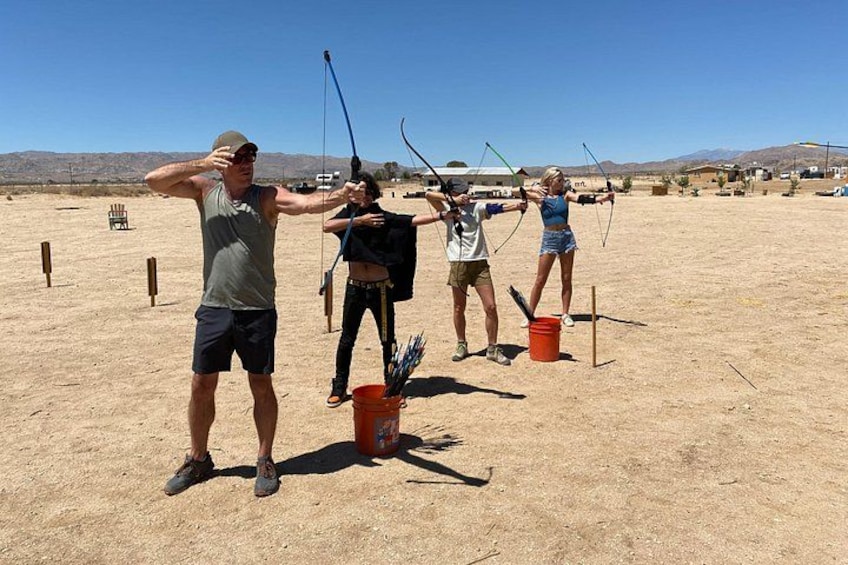 People practicing archery in an open field with mountains in the background. 5