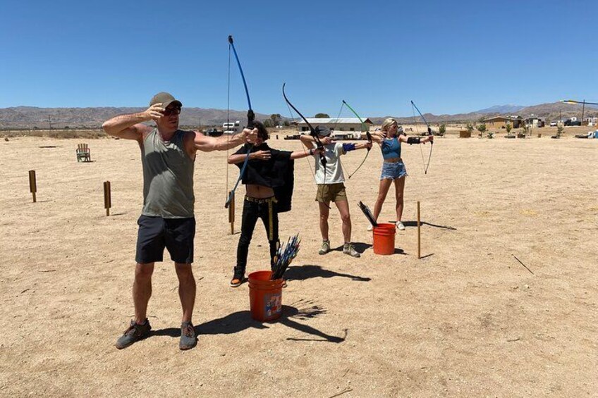 People practicing archery in an open field with mountains in the background. 5