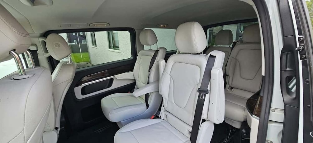 A car interior with beige leather seats and a sunroof. 4