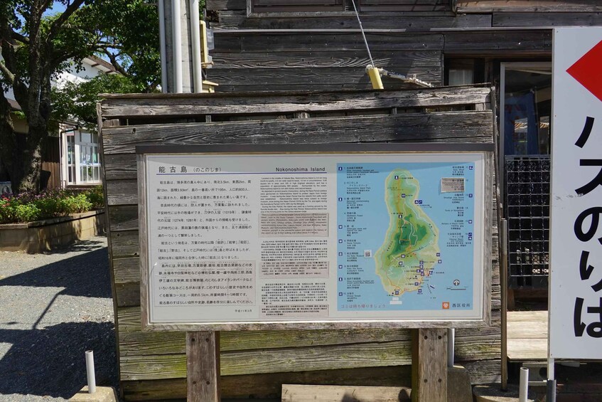 A wooden signboard with information about Noko Island and a map. 3
