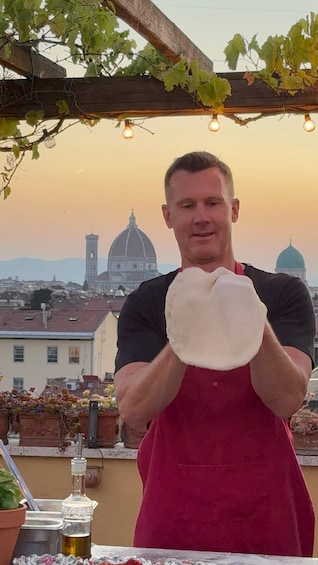 A person holding a flatbread outdoors with a cityscape and a dome structure in the background. 2