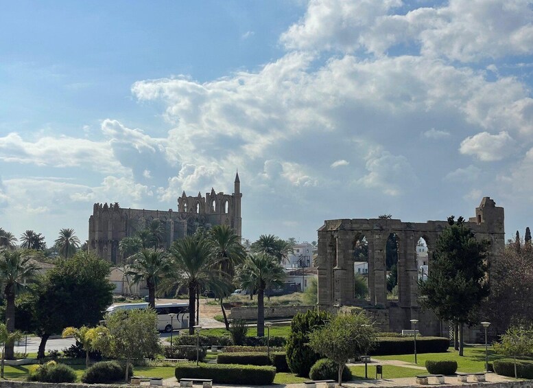 A historic cathedral with ruins and palm trees in the foreground. 1