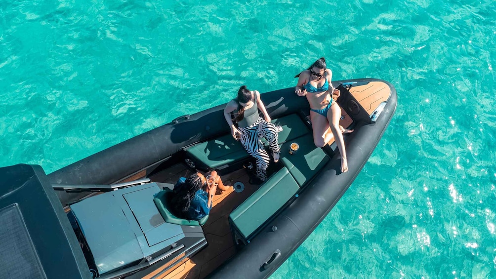A small inflatable boat on turquoise water with three people on board. 4