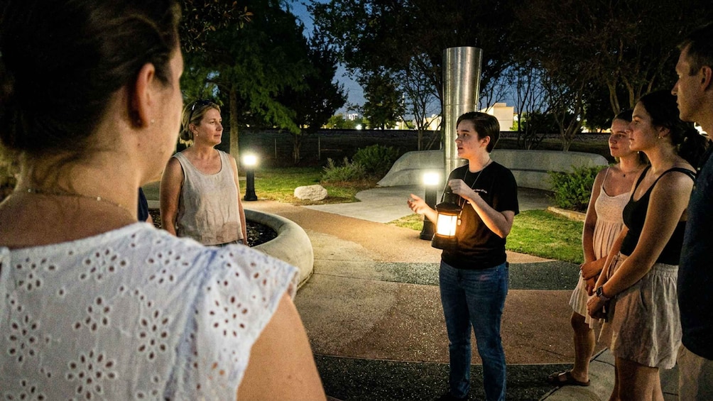 A group of people gathered around a fountain at night. 1
