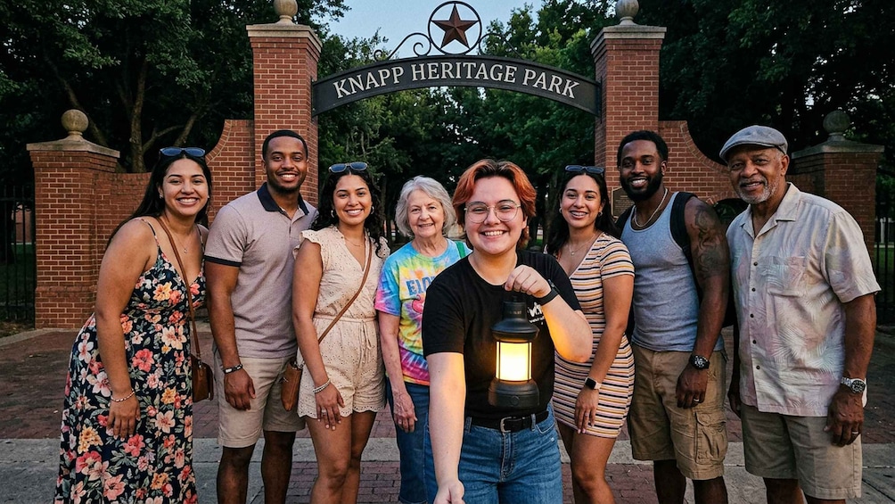 A group of people standing in front of the Knapp Heritage Park sign. 2