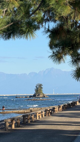 A coastal scene with a rocky breakwater, a lighthouse, and mountains in the background. 2