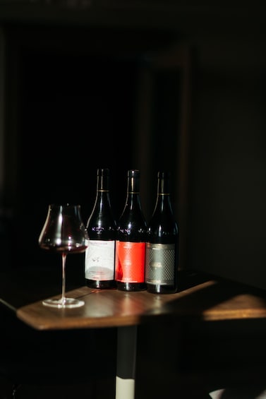 Three wine bottles and a wine glass on a table. 2