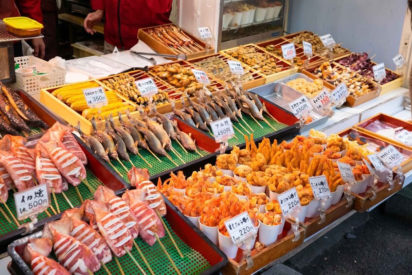 A variety of seafood and meat skewers and sticks for sale at a market. 3