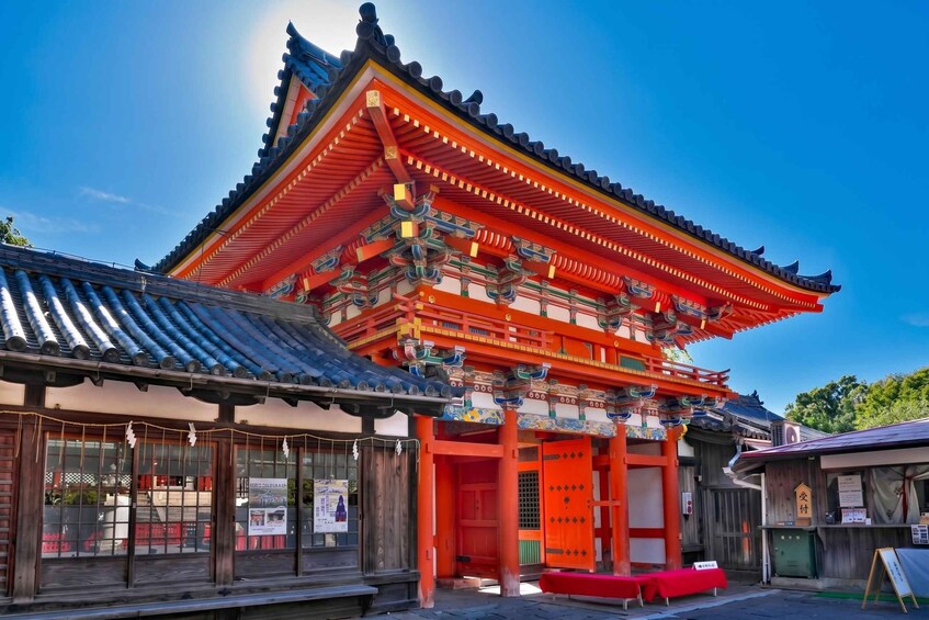 A traditional Japanese building with a bright red and orange facade, a tiled roof, and wooden structures. 1
