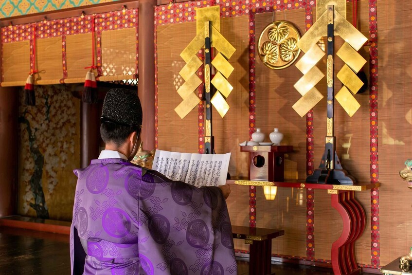 A person in traditional attire reading a paper in a room with wooden walls and decorative elements. 3
