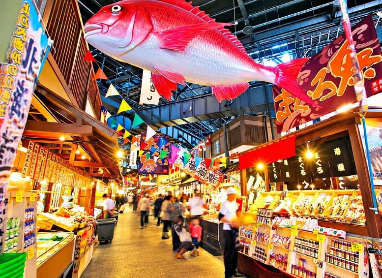 Een levendige overdekte markt met kleurrijke vlaggen en een grote decoratie van een vis. 2
