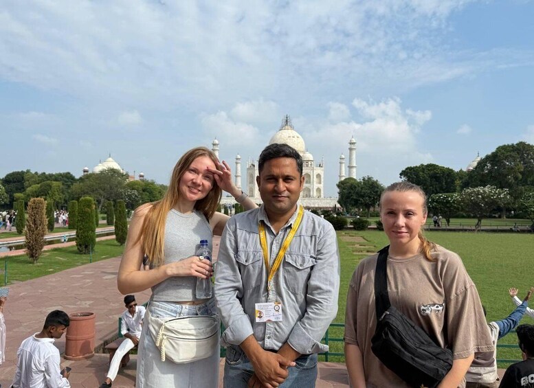 Three people standing in front of the Taj Mahal with a clear sky. 2