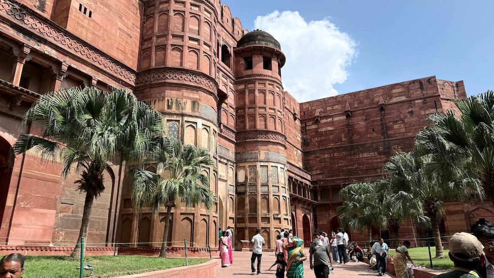 A historic building with intricate architecture and palm trees in the courtyard. 4
