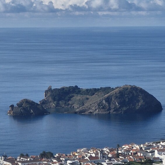 A coastal town with a prominent rocky island in the sea. 2