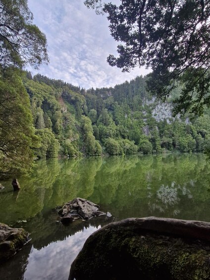 A calm lake surrounded by dense forest and rocky cliffs. 1