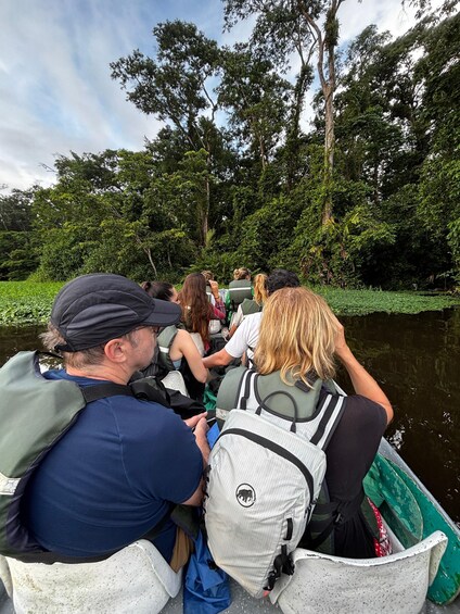 A group of people on a boat in a forested area. 1