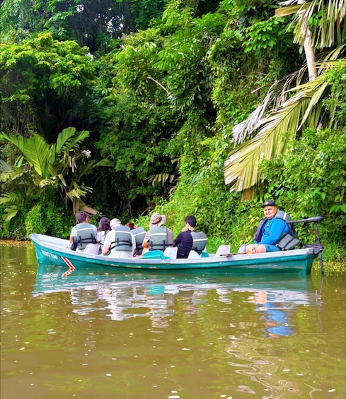 A boat with passengers on a river surrounded by dense greenery. 1