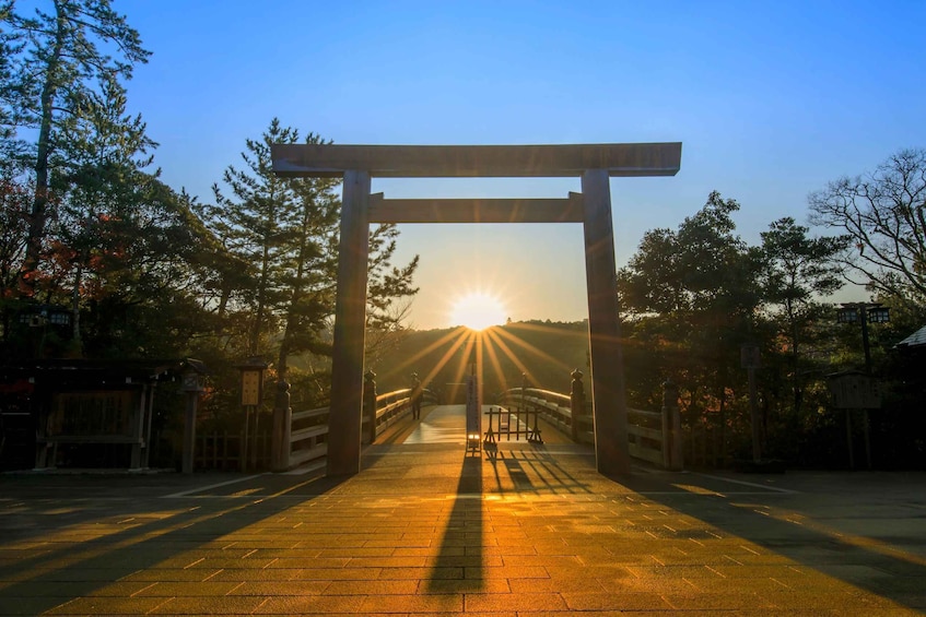 A traditional Japanese torii gate at sunrise with sunlight streaming through. 1