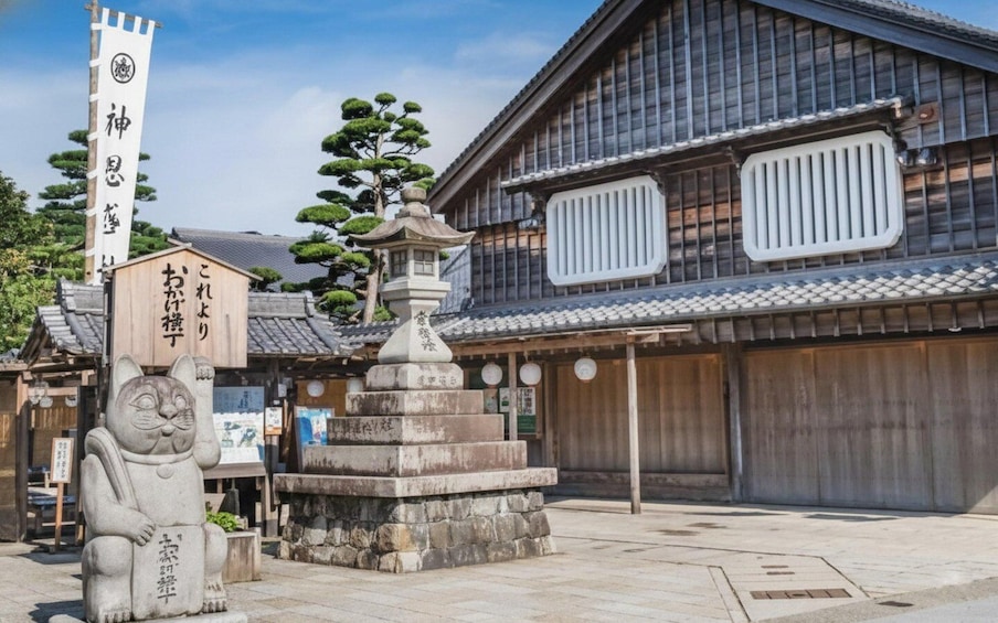 A traditional Japanese building with a stone lantern and a stone statue of a cat. 3