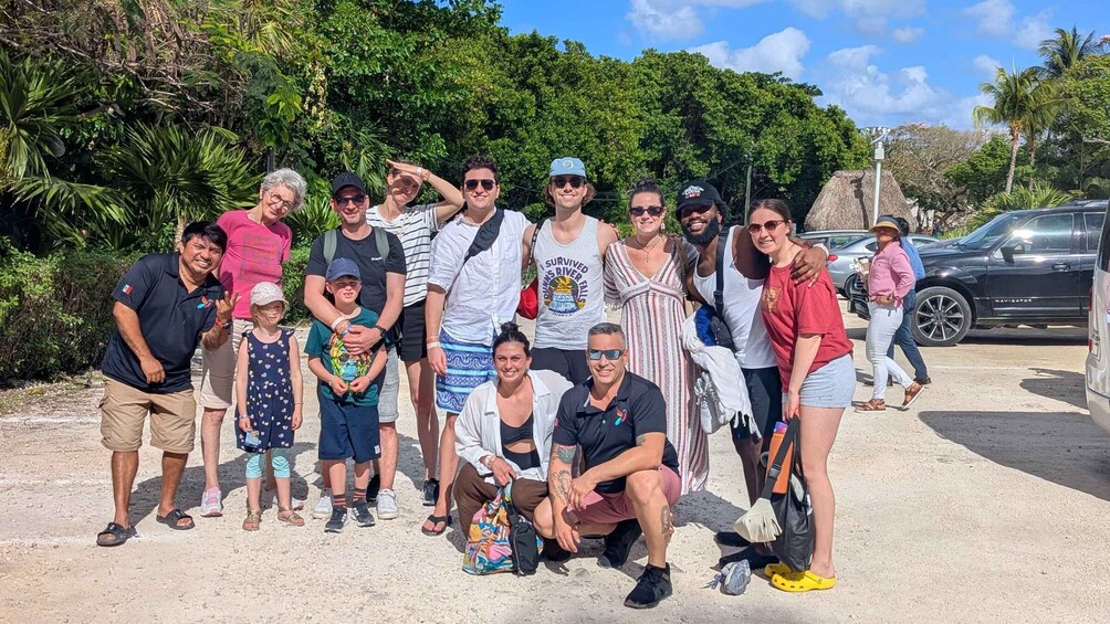 A group of people posing outdoors with a tropical background. 2