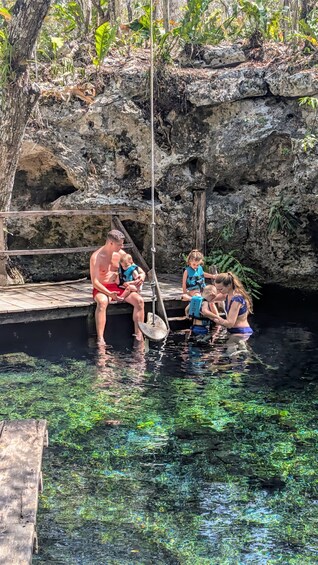 A family by a clear pool with rocky cliffs in the background. 5