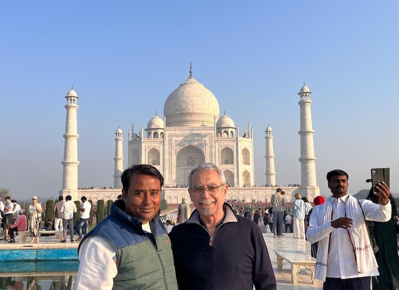 The Taj Mahal with two men in front, one taking a photo. 3