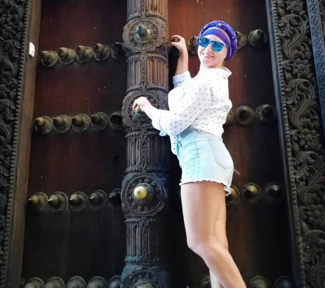 A person leaning against an ornate door with intricate metalwork and decorative elements. 3
