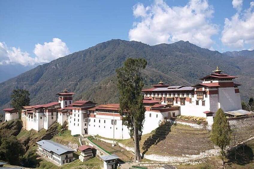 A monastery with multiple buildings, surrounded by mountains and trees. 3