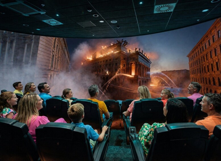 An audience seated in a theater watching a fire-damaged building on stage. 1