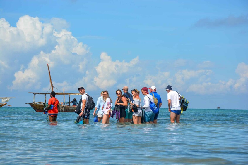 A group of people standing in shallow water near a boat. 4