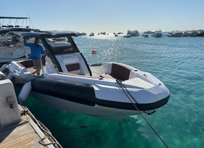 A small motorboat docked at a marina with other boats in the background. 5