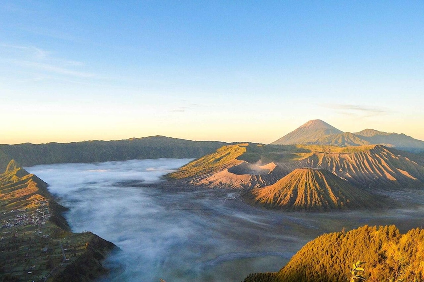 A volcanic landscape with a prominent mountain, a valley with a river, and a town at the base. 3