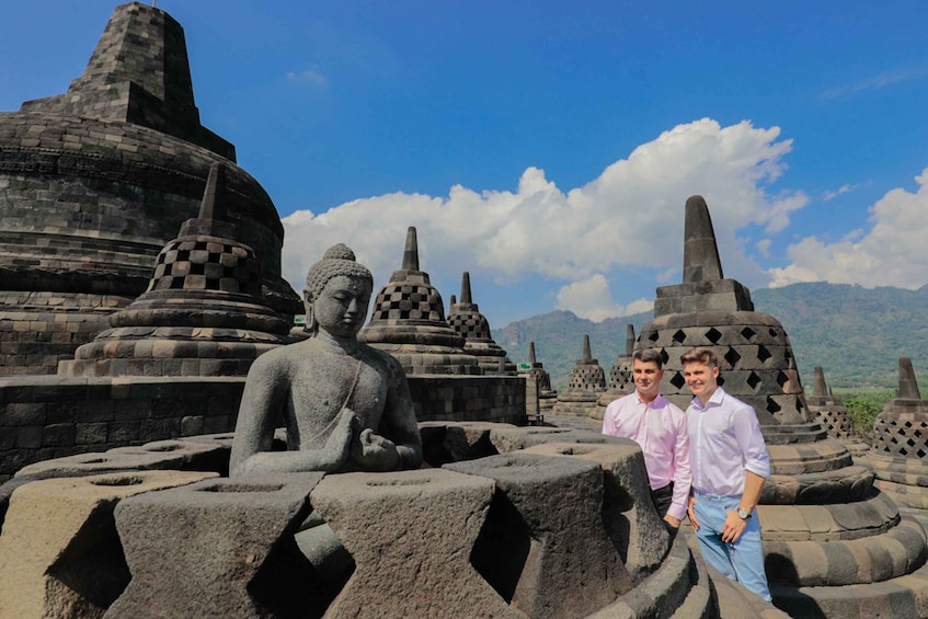 A large Buddha statue surrounded by ancient stone structures and mountains in the background. 5