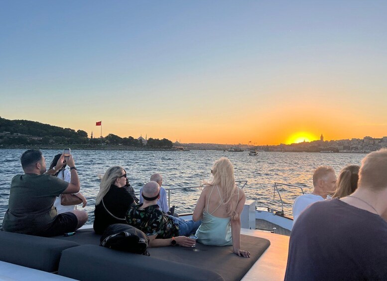 People on a boat watching a sunset over a body of water with a city skyline in the background. 4
