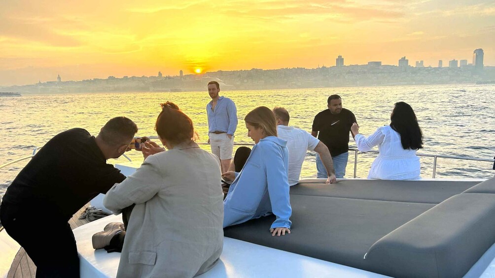 A group of people on a boat during sunset with a city skyline in the background. 2