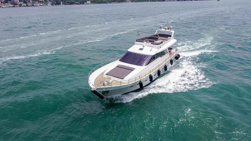 A white motor yacht with a cabin and a sunroof, moving through turquoise waters. 5