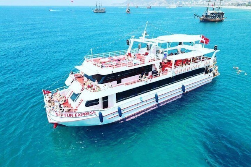Un gran ferry blanco llamado N.P.T.U.N. EXPRESS navegando sobre un mar azul despejado, con otros barcos a lo lejos. 1